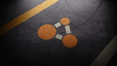Orange connected-node symbol on a dark road surface with yellow lane markings