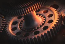 Close-up of interlocking metal gears illuminated by warm orange light