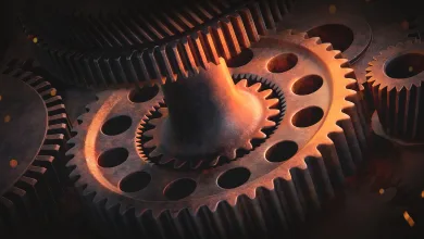 Close-up of interlocking metal gears illuminated by warm orange light