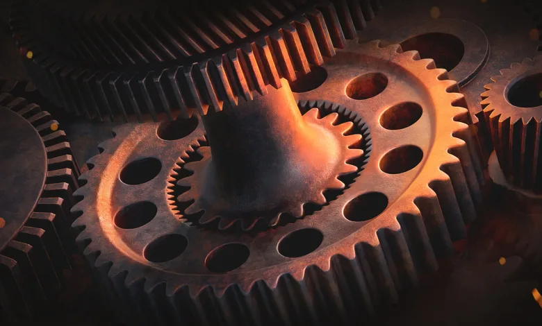 Close-up of interlocking metal gears illuminated by warm orange light