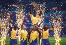 Rematch players in yellow and blue kits lift a trophy as fireworks erupt in a stadium
