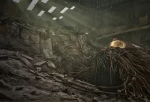 A large damaged metal structure covered in hanging cables sits amid rubble inside a ruined reactor chamber.