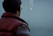 A person in a dark beanie and red vest stands in a foggy Silent Hill setting