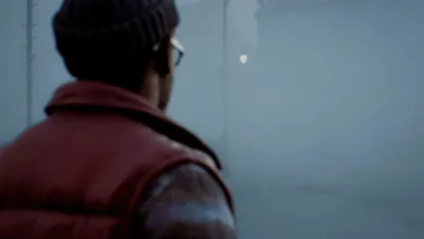 A person in a dark beanie and red vest stands in a foggy Silent Hill setting