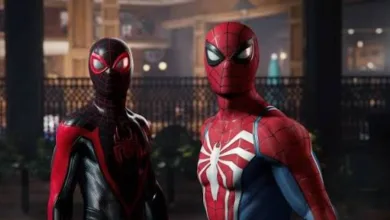 Two Spider-Man characters, one in a red-and-blue suit and one in a black-and-red suit, stand indoors