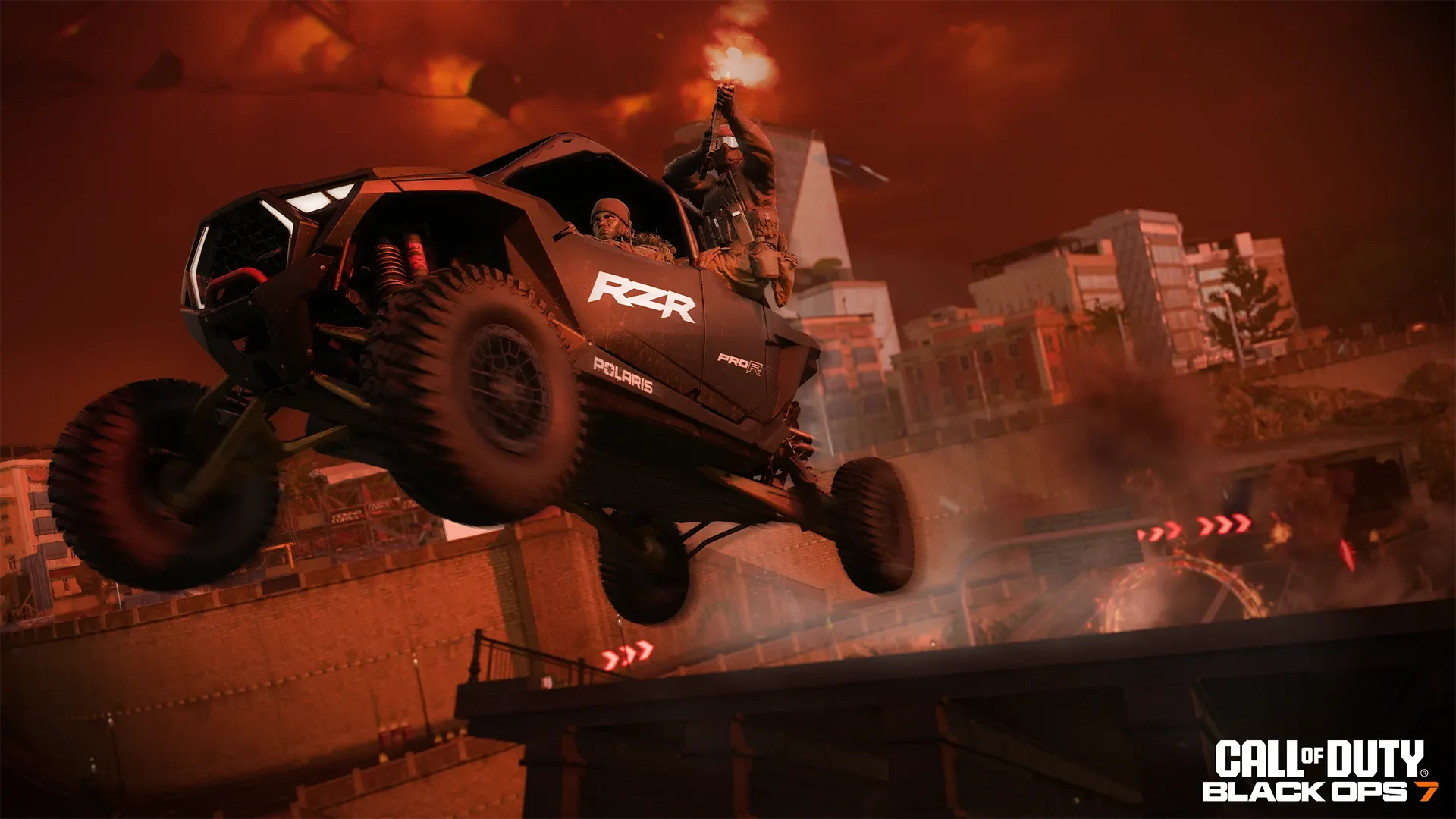 An off-road vehicle carrying armed operators leaps through a fiery, smoke-filled city.