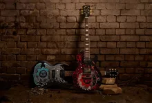 Two custom Gears of War: E-Day Gibson guitars displayed against a brick wall