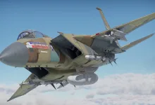 A fighter aircraft carrying multiple missiles flies above the clouds
