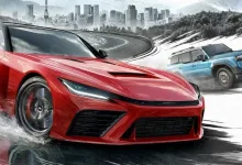 A red sports car drives through water on a mountain road while a blue SUV follows, with a city skyline in the background