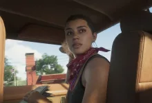 A woman wearing a red bandana sits inside a car with a city street visible through the windows.