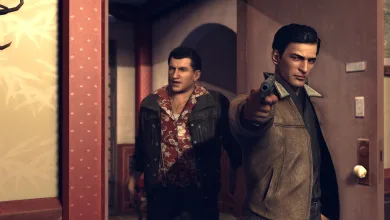 Two men stand in a hallway as one points a pistol toward the viewer in Mafia 2.