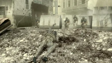 Snake lies prone in a damaged urban street while soldiers approach in Metal Gear Solid 4