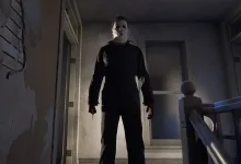 Michael Myers stands in a dim hallway in Halloween: The Game.