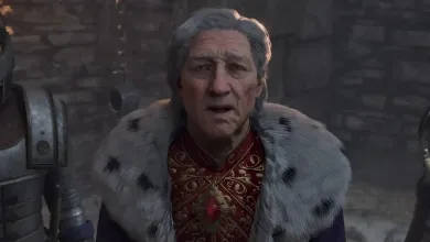 A gray-haired character in ornate red clothing and a fur-lined cloak stands in a stone setting in Oblivion Remastered.