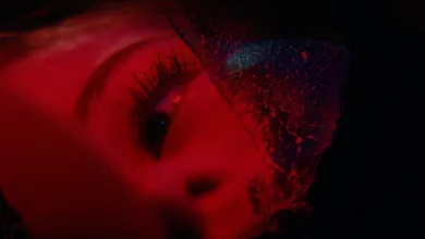 A red-lit close-up of a face partially obscured by a textured material in Precognition.