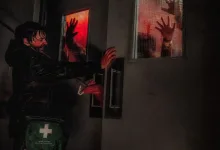 A man reaches toward a hospital door as shadowy hands press against red-lit windows.