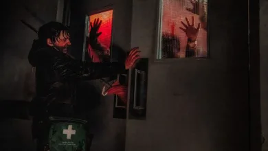 A man reaches toward a hospital door as shadowy hands press against red-lit windows.