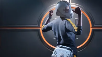A THE FINALS contestant wearing a gray protective hood, striped shirt, and silver equipment pack in front of a circular orange-lit door.