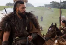 Uli Latukefu in historical costume standing beside a horse in a grassy camp