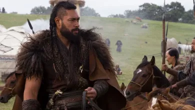 Uli Latukefu in historical costume standing beside a horse in a grassy camp