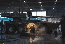 Armored military vehicles undergoing maintenance inside a large hangar