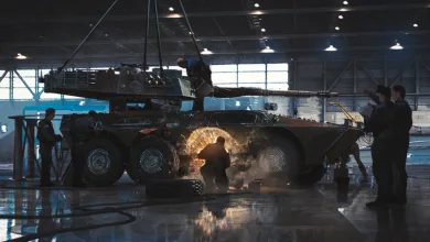 Armored military vehicles undergoing maintenance inside a large hangar