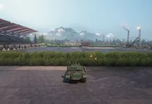 A World of Tanks vehicle sits on a paved area beside a racetrack-like circuit with mountains in the background.