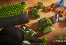 Xbox 25th Anniversary keyboard, mouse, controllers, charging accessories, and other green and translucent gaming hardware arranged on a wooden table.