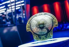 The International Aegis trophy displayed on a stand against blue and red event lighting.