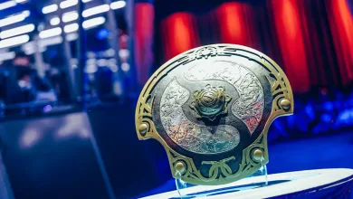 The International Aegis trophy displayed on a stand against blue and red event lighting.