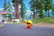 PAC-MAN stands on a Fortnite road beside a gas station and tall redwood trees.