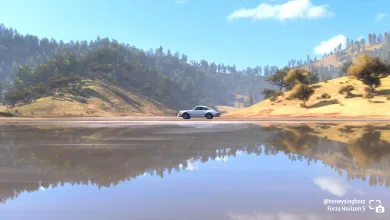 A car drives beside a calm lake in Forza Horizon 5, creating a clear reflection in the water