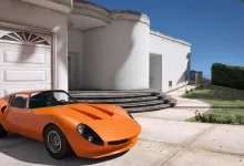 An orange sports car sits outside a white modern house in Grand Theft Auto V.