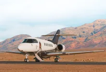 A Hawker 800XP business jet sits on a runway with mountains behind it.