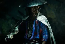A samurai in Onimusha: Way of the Sword holds a sword beneath a conical hat in a dark setting.