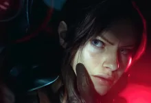 Close-up of a woman in dark clothing, her face illuminated by red and blue light.