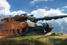 A modern tracked tank moves across grassy terrain with snow-capped mountains in the background