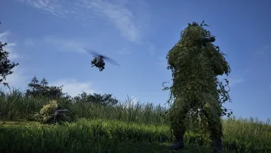 A camouflaged WARDOGS soldier stands in tall grass while another soldier lies nearby and a helicopter flies overhead.