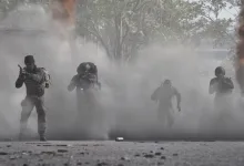 Four WARDOGS soldiers move through a smoke-filled battlefield.