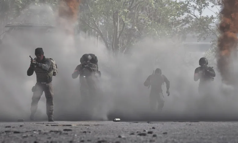 Four WARDOGS soldiers move through a smoke-filled battlefield.