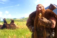 A bearded dwarf holding a small flower stands in a sunlit meadow with mountains in the background.