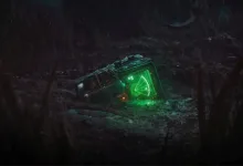 A glowing green motion tracker lies on the ground in a dark outdoor setting.
