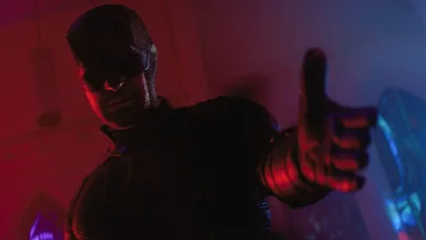 Daredevil reaches toward the camera in red and blue lighting.