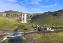 An in-game view of a waterfall, roadside parking area and vehicles in Iceland.