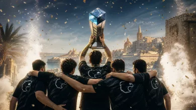 Five esports players in black jerseys celebrate together as one raises a trophy above them, with confetti and a coastal city in the background.