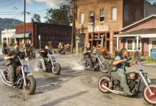 Several bikers ride past storefronts on a street in Grand Theft Auto VI.