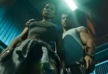 A woman and man stand together with firearms in a dim, blue-lit interior in Grand Theft Auto VI.