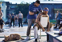 A man trims a seated customer’s hair on a lively neighborhood street in Grand Theft Auto VI.