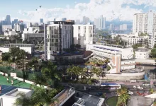 A bright urban neighborhood in Grand Theft Auto VI, with high-rise buildings, a basketball court, palm trees, and traffic.