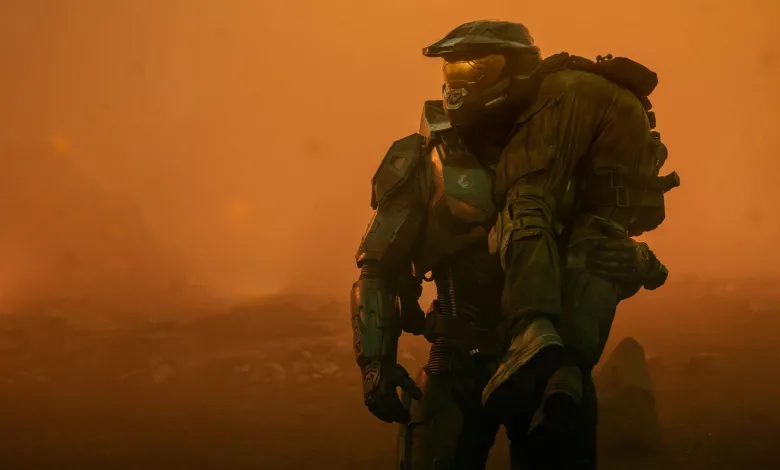 A green-armored Halo Spartan kneels in an orange haze.